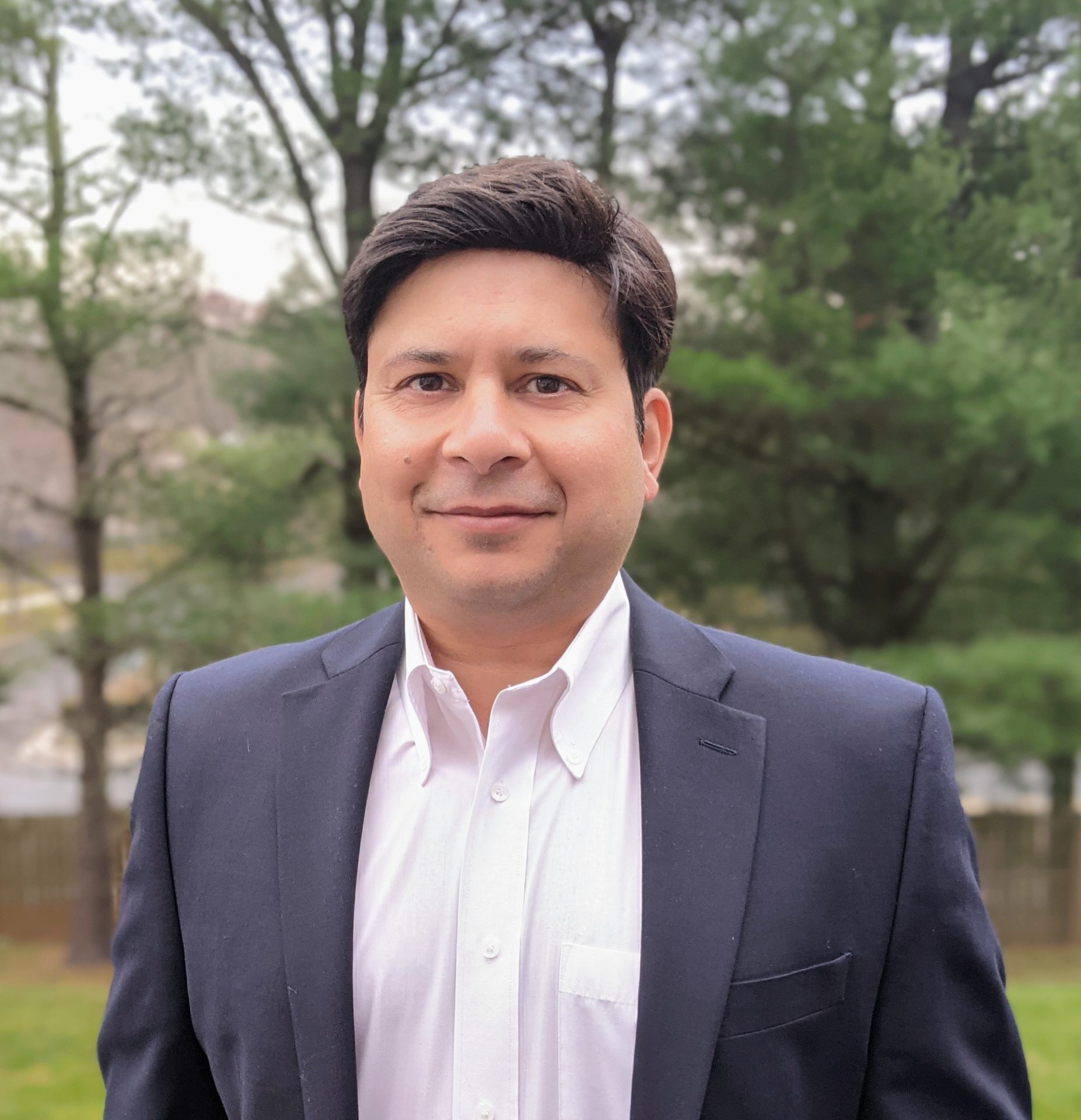 Headshot of man standing in front of trees
