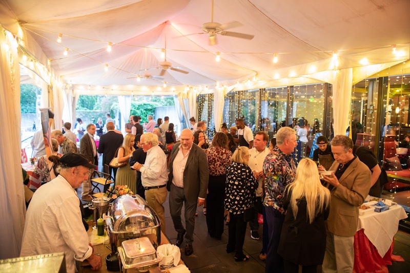 group of people under large tent eating food