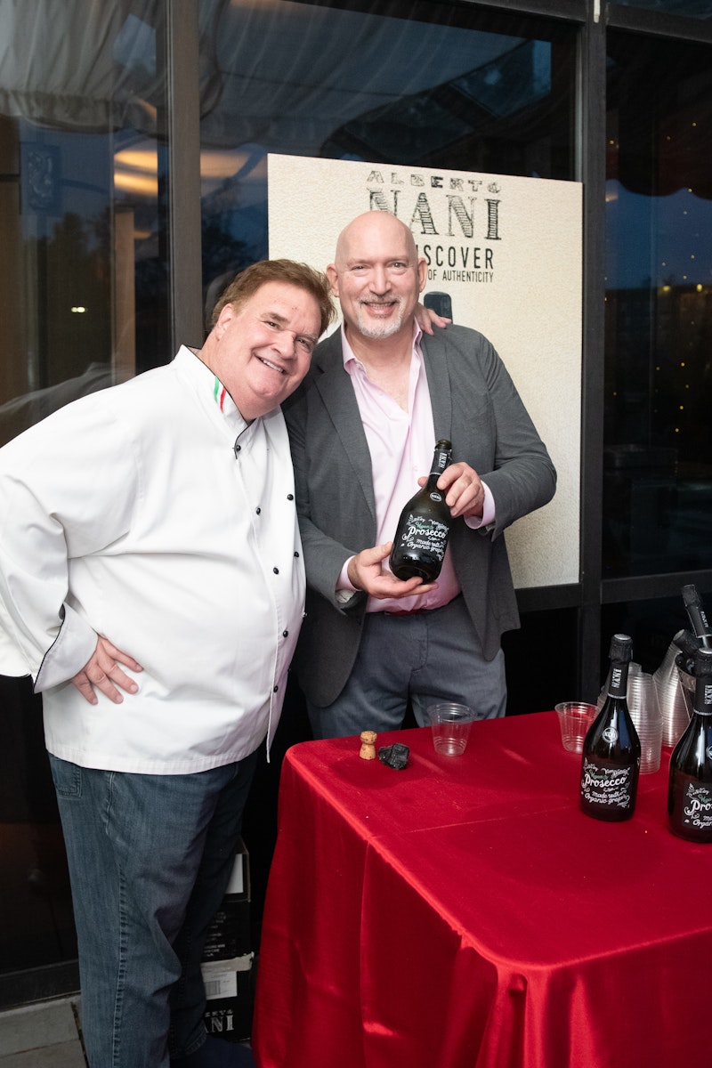 two men smiling with wine bottle