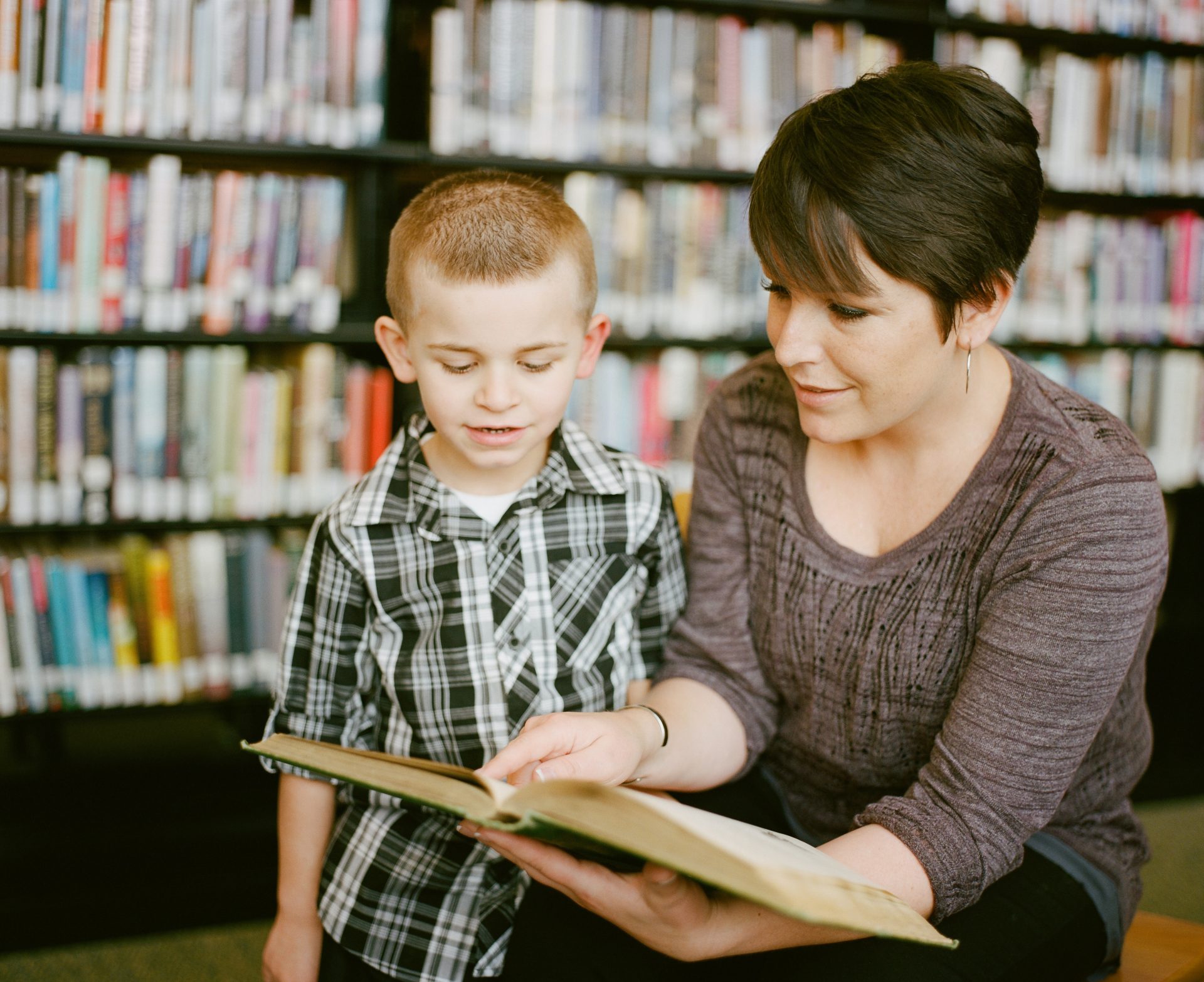 Woman reading aloud with little boy in a library